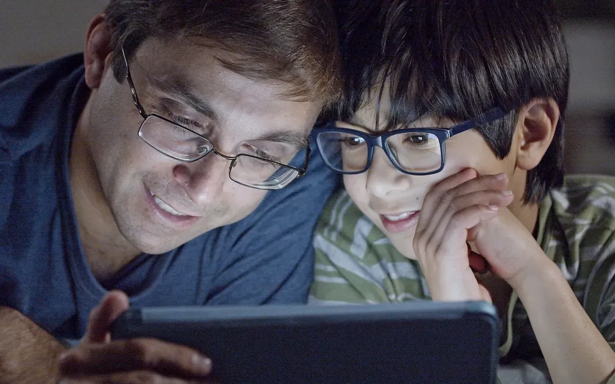 Un père et son fils regardent ensemble une tablette