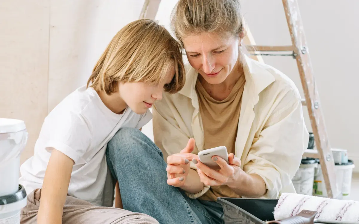 A mother and her son looking at a smartphone together