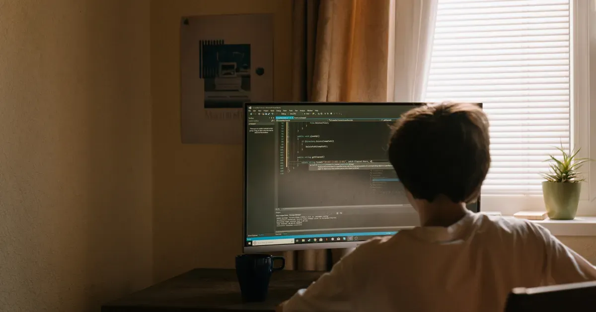 Un ragazzo seduto da solo nella sua stanza davanti al computer