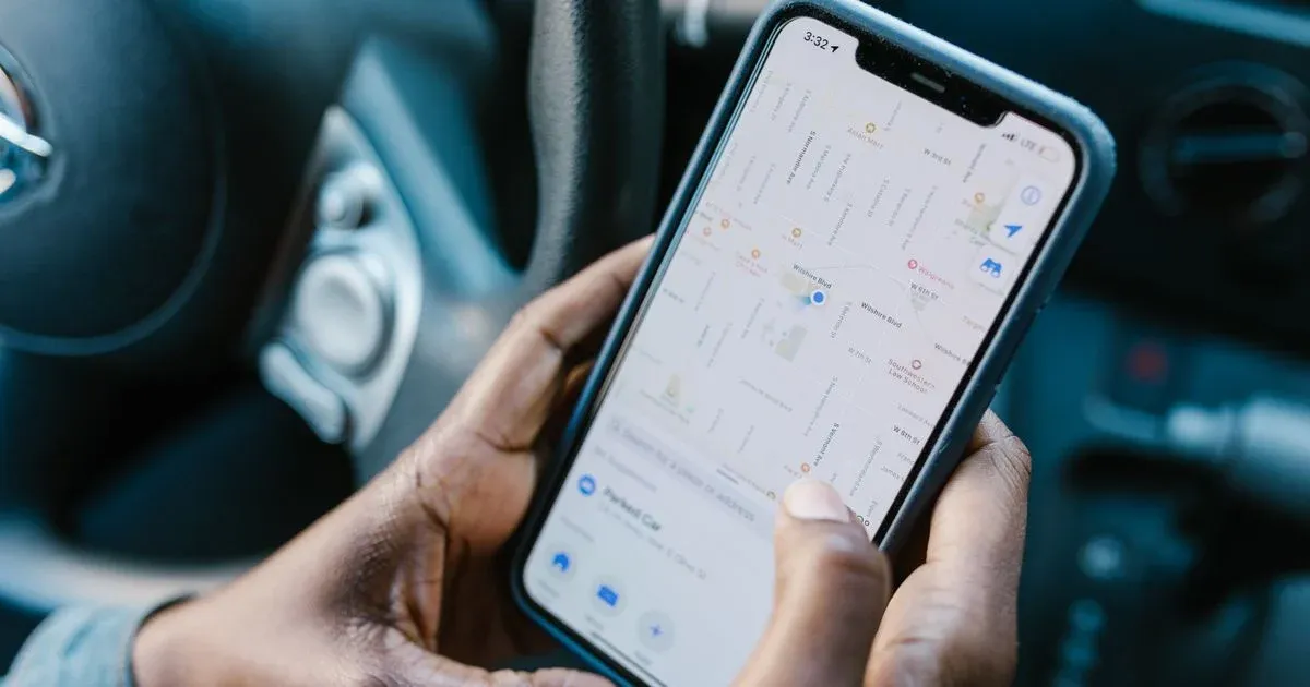Smartphone con un mapa abierto en la mano de una persona dentro de un coche