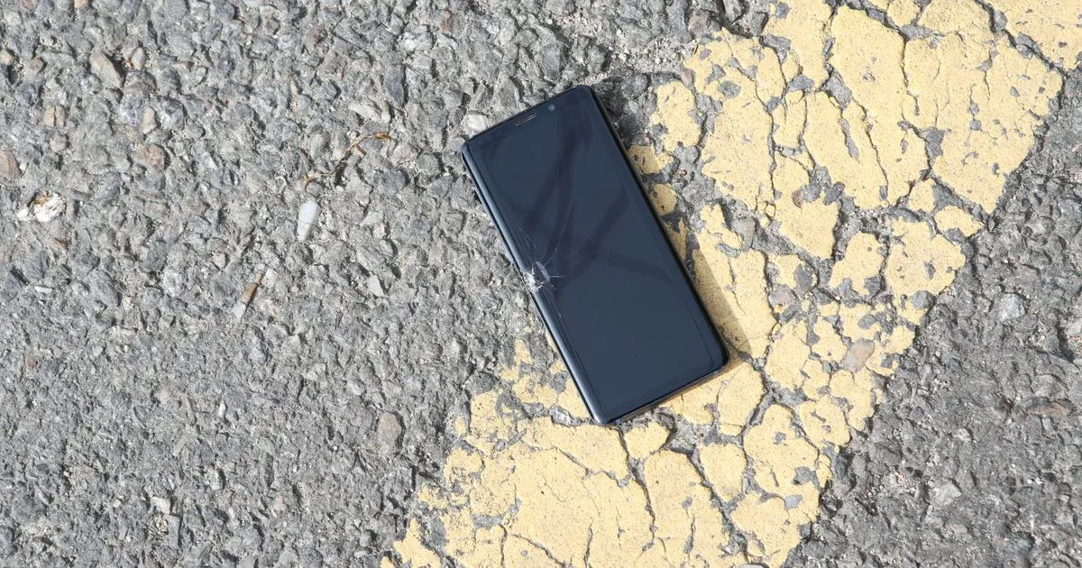 Un smartphone perdu posé sur l'asphalte d'une route
