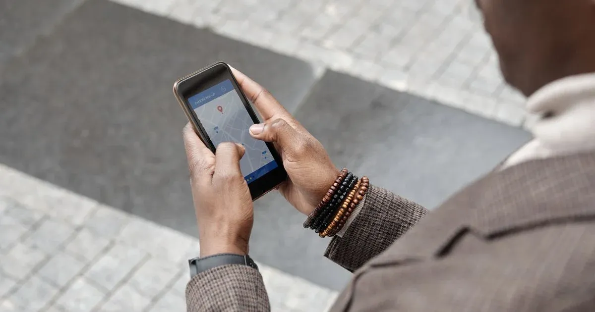 Ruce držící chytrý telefon s mapou na ulici