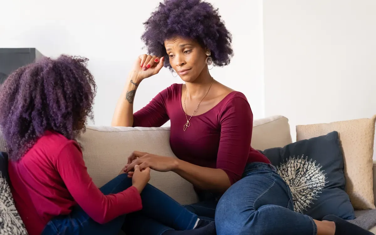 Una madre y su hija hablan sentadas en el sofá