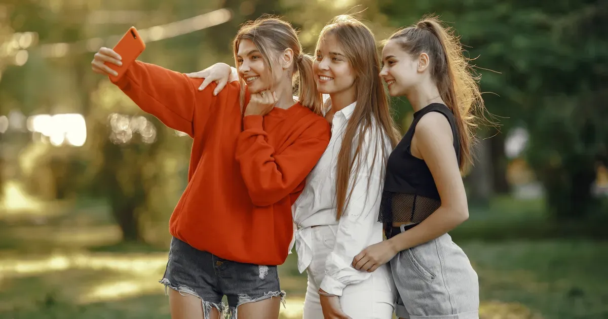 Drei Jugendliche machen im Park ein Selfie mit dem Smartphone