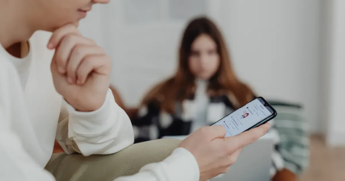 A teenage boy scrolling on a smartphone on the couch